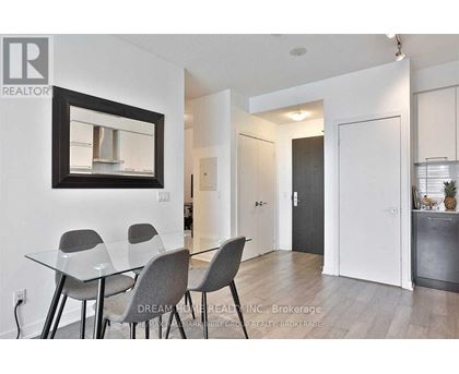 A dining room with a glass table and grey chairs.