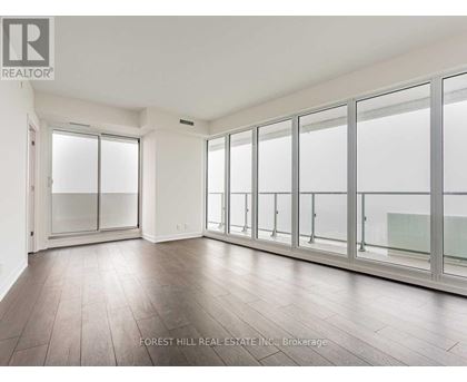 A spacious room with wooden floors and large windows.