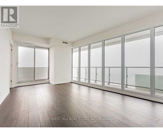 A spacious room with wooden floors and large windows.