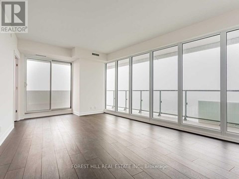 A spacious room with wooden floors and large windows.