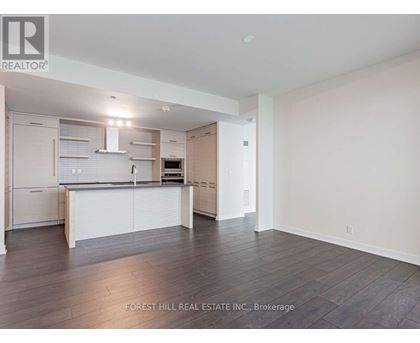 A spacious kitchen with white cabinets and a wooden floor.