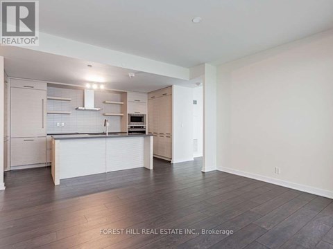 A spacious kitchen with white cabinets and a wooden floor.