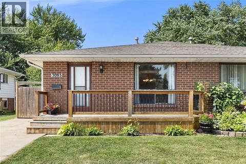 A house with a brown brick exterior and a wooden deck.