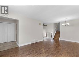 A spacious room with wooden floors and a staircase leading to another level.
