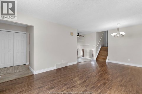 A spacious room with wooden floors and a staircase leading to another level.