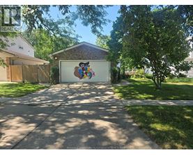 A garage with a mural on the door is surrounded by a well-kept lawn and trees.
