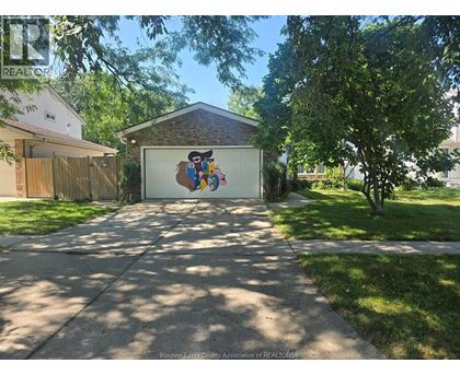 A garage with a mural on the door is surrounded by a well-kept lawn and trees.