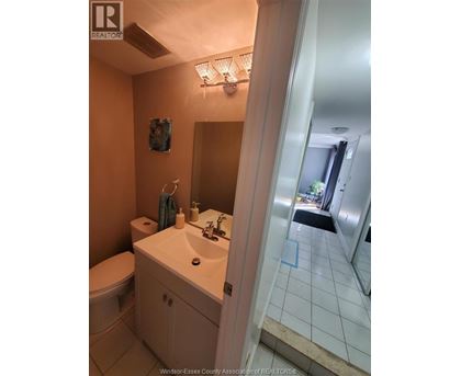 A bathroom with a toilet, sink, and mirror.