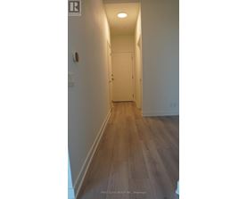 A hallway with wood floors and white walls.