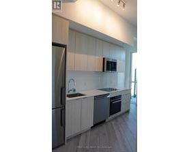 A modern kitchen with a refrigerator, sink, and oven.