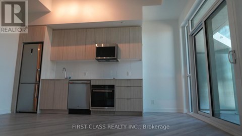 A modern kitchen with wooden cabinets and a flat screen TV mounted above the island.
