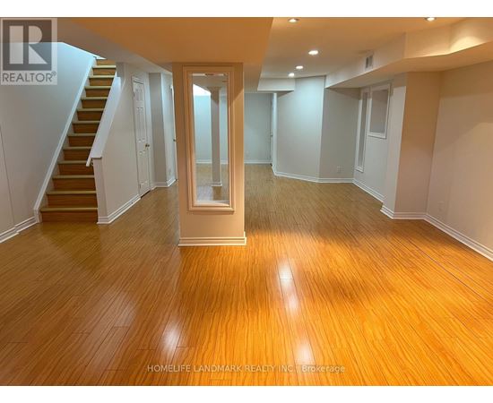 A spacious room with wooden flooring and a staircase leading to another level.