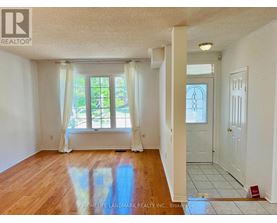 A room with wooden floors and white walls, with a window and a door visible.