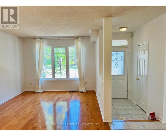 A room with wooden floors and white walls, with a window and a door visible.