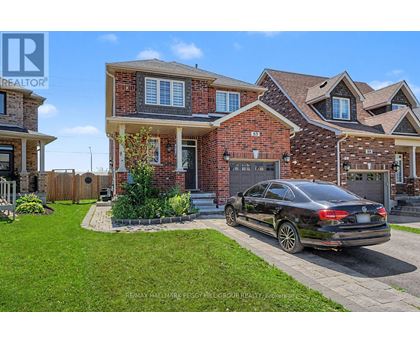 A black car is parked in front of a brick house.