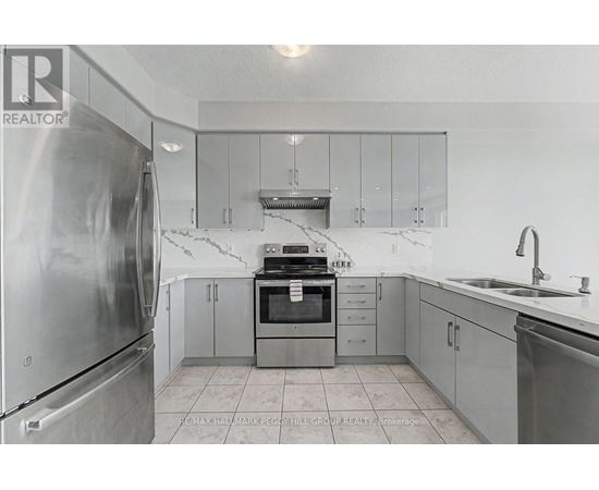 A kitchen with a refrigerator, oven, and sink.