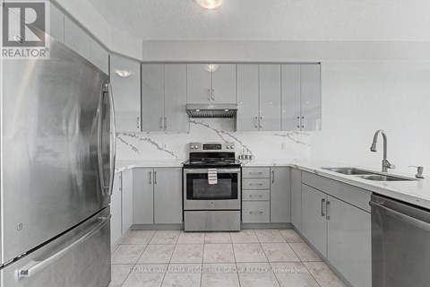 A kitchen with a refrigerator, oven, and sink.