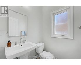 A white bathroom with a toilet, sink, and mirror.