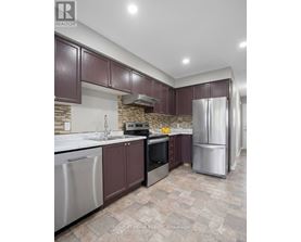 A kitchen with brown cabinets and a stone backsplash.