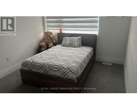 A bedroom with a bed and a teddy bear on the windowsill.