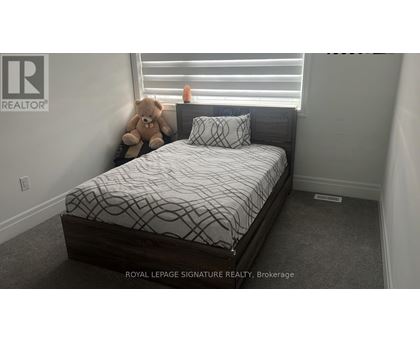 A bedroom with a bed and a teddy bear on the windowsill.