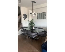 A modern dining room with a glass table and grey chairs.