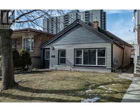A house with a grey siding and a white roof is for sale.
