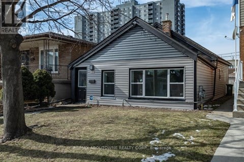 A house with a grey siding and a white roof is for sale.