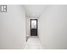 A hallway with a black door and tiled floor.