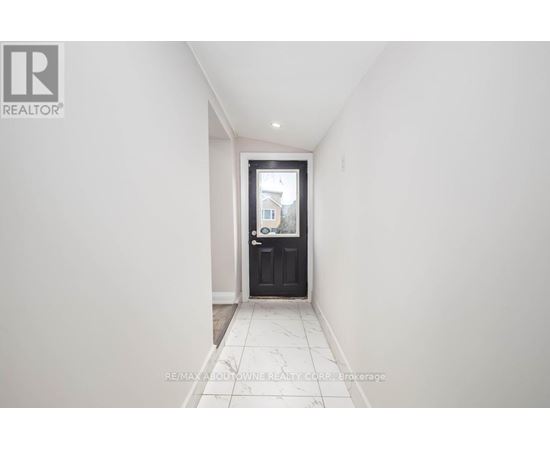 A hallway with a black door and tiled floor.