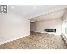 A spacious room with wooden flooring and a flat screen TV mounted on the wall.