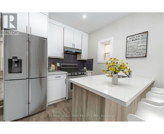 A kitchen with a refrigerator, stove, and white cabinets.