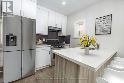 A kitchen with a refrigerator, stove, and white cabinets.