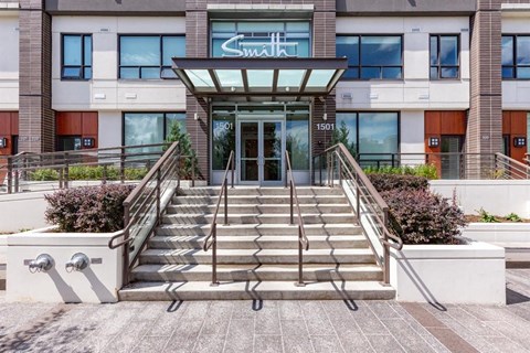 The front of a building with a glass entrance and stairs leading up to it.