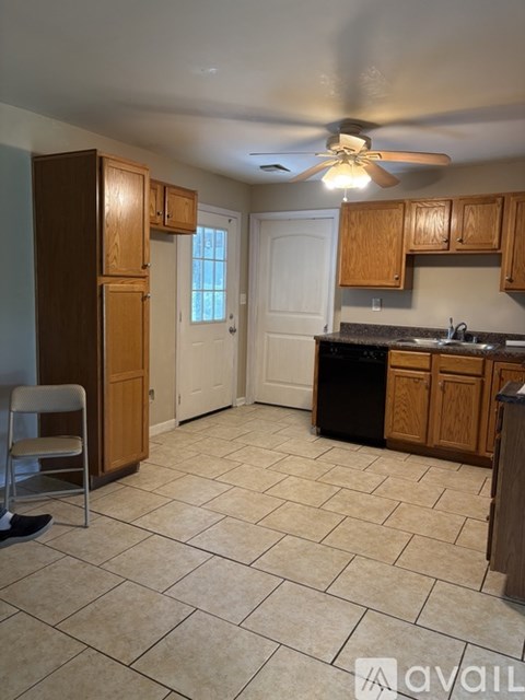 A kitchen with wooden cabinets and a black trash can.