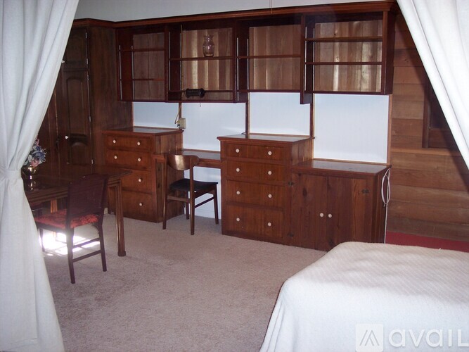 A bedroom with a bed, dresser, and chair.