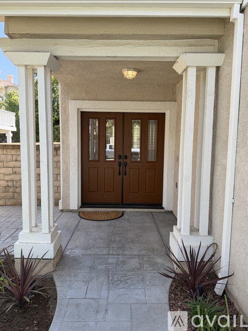 A brown double door is flanked by white columns.