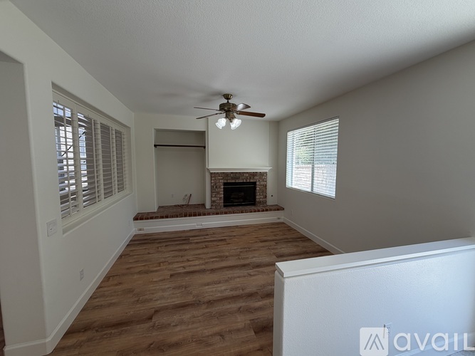 A spacious living room with a fireplace and a ceiling fan.