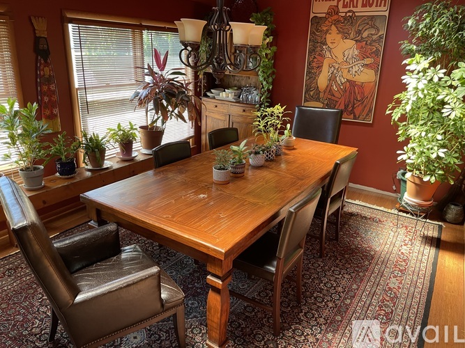 A dining room with a wooden table surrounded by chairs.