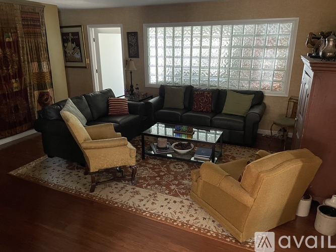 A living room with a black couch, a yellow chair, and a coffee table.