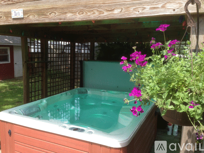 A hot tub with a wooden cover and purple flowers in a pot.