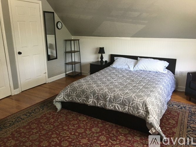 A bedroom with a bed, nightstand, and a rug.