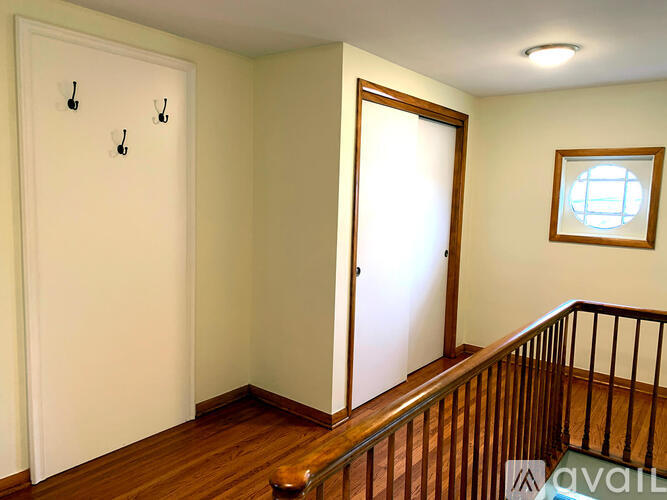 A room with a wooden floor, a white door, a window, and a staircase.