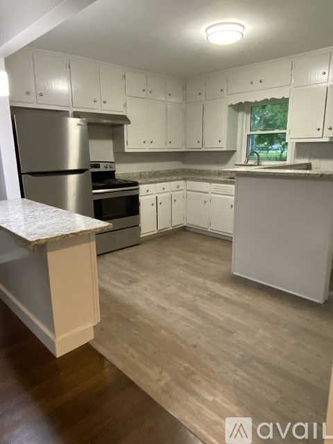 A kitchen with white cabinets and a wooden floor.