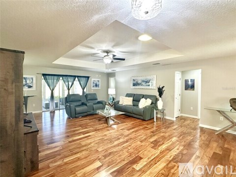 A living room with a grey couch and a wooden floor.