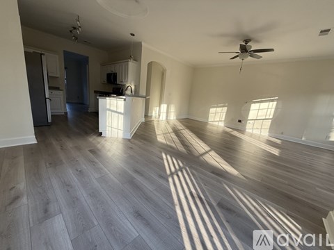 A spacious living room with wooden flooring and a ceiling fan.