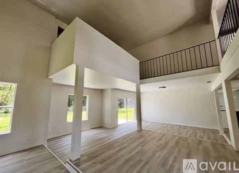 A spacious living room with a balcony and hardwood floors.
