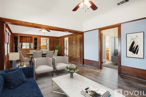 A living room with a dark blue couch and a coffee table with a vase of flowers on it.