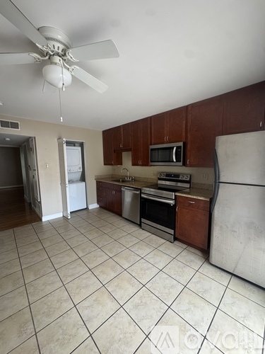 A kitchen with brown cabinets and a white ceiling fan.