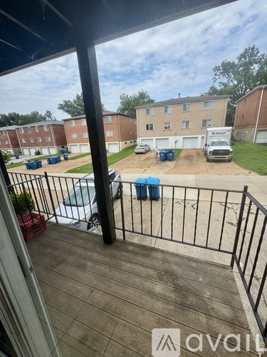 A balcony view of a parking lot with cars and apartment buildings.